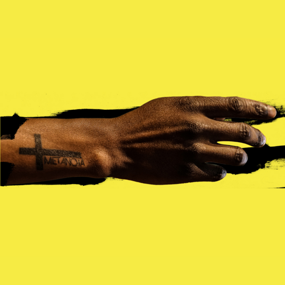 project image featuring a photo of Jawanza Williams' hand with tattoo that says "Metanoia" over black paint brush stroke on a saturated yellow background